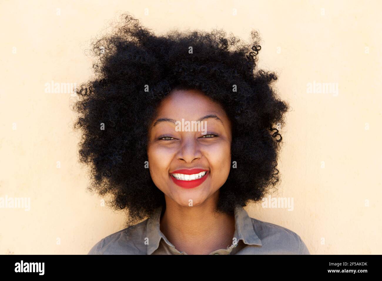 Close up portrait of beautiful young black woman standing and smiling ...