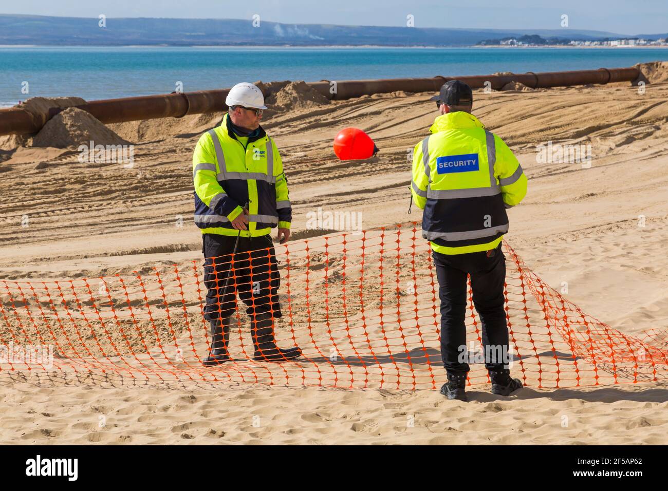 Insight Security personnel on beach for safety for beach replenishment work at Bournemouth and Poole beaches, Dorset UK in March Stock Photo