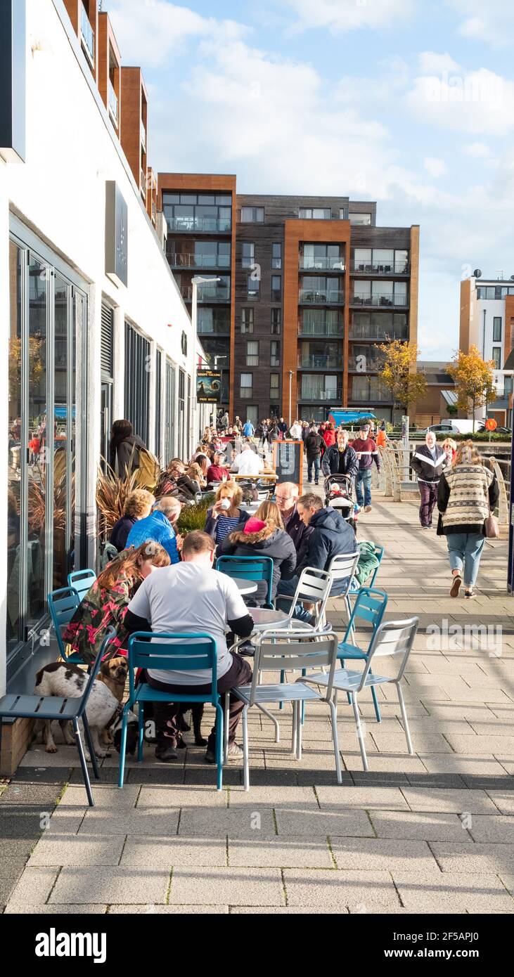 A view of Portishead Quays Marina. The image shows people enjoying warm weather and sitting outside coffee shops and bars at the far end of the marina Stock Photo