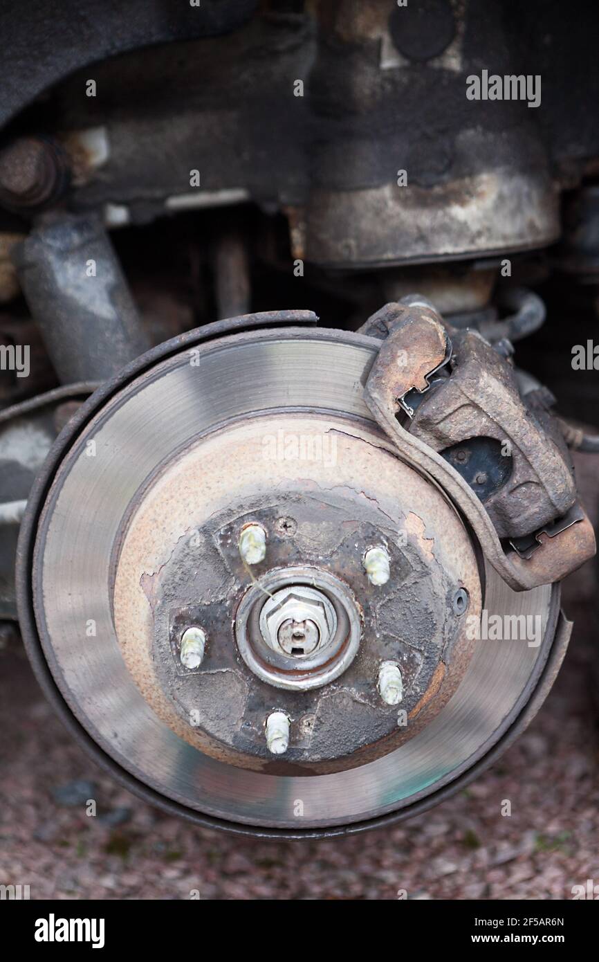An old steel ventilated brake disk with used brake pads are ready for removing, rear wheel Stock Photo