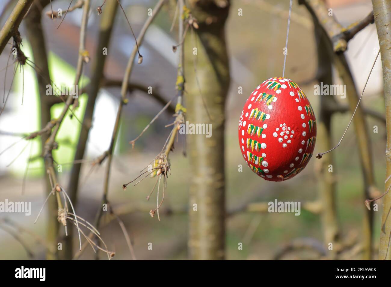 red painted and colored easter egg hanging on a twig Stock Photo