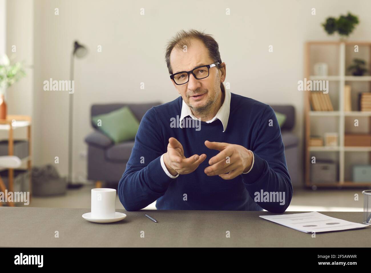 Middle-aged male psychotherapist lists the patient's problems by talking to him via video link. Stock Photo