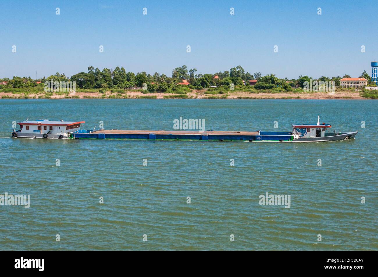 Barge on the Mekong. This is so fully loaded that the waterline almost crosses the railing. Stock Photo