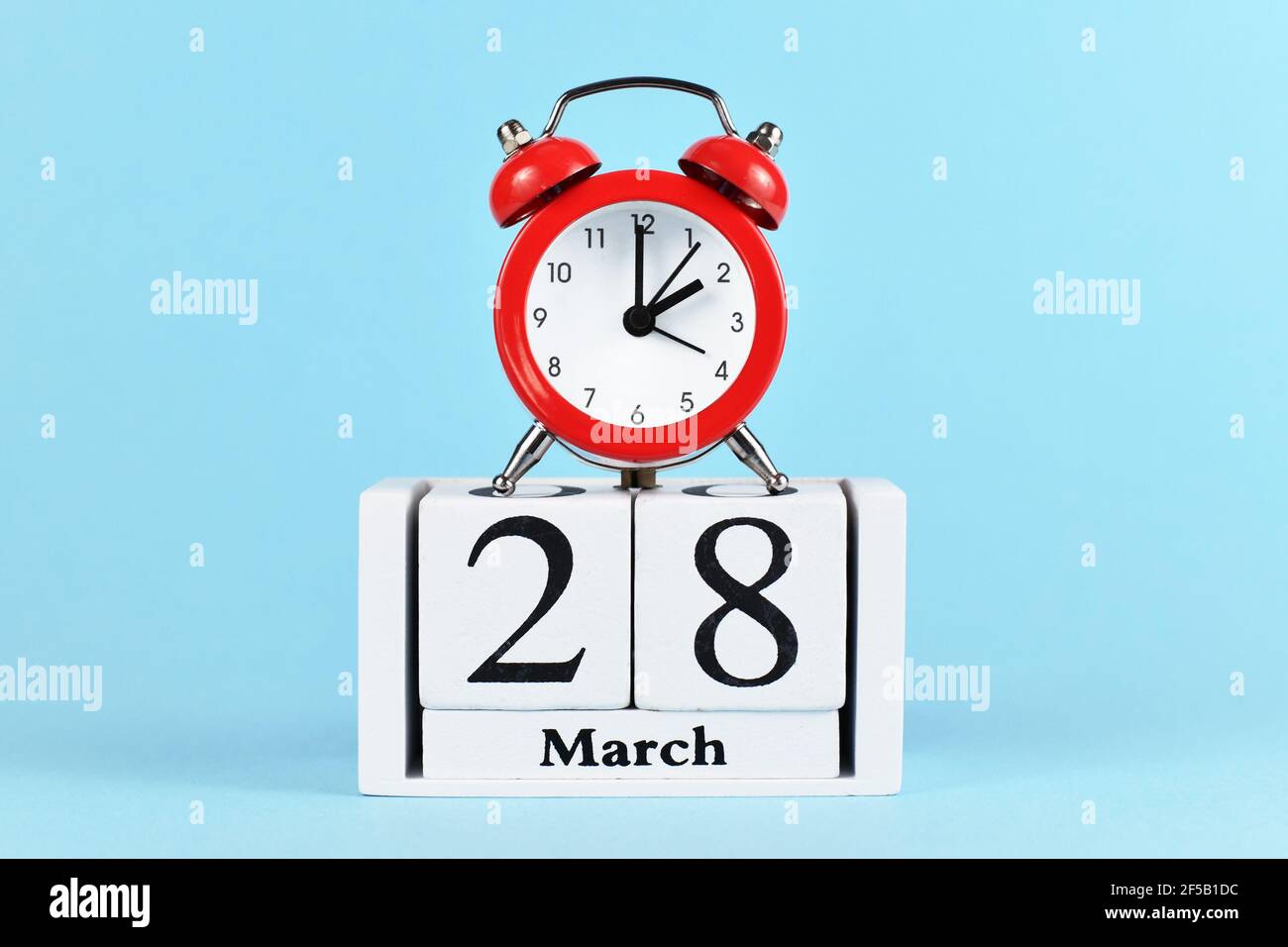 Time change for daylight saving summer time in Europe on March 28th concept with red alarm clock and calendar on blue background Stock Photo