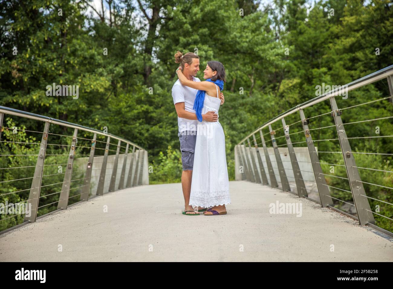 Cute Caucasian couple hanging a lock on the bridge as a sign of eternal ...