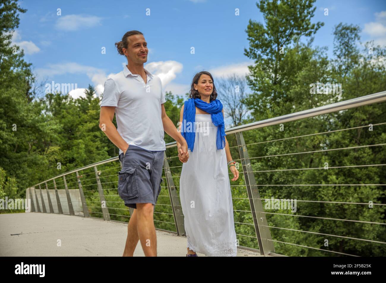 Cute Caucasian couple hanging a lock on the bridge as a sign of eternal ...