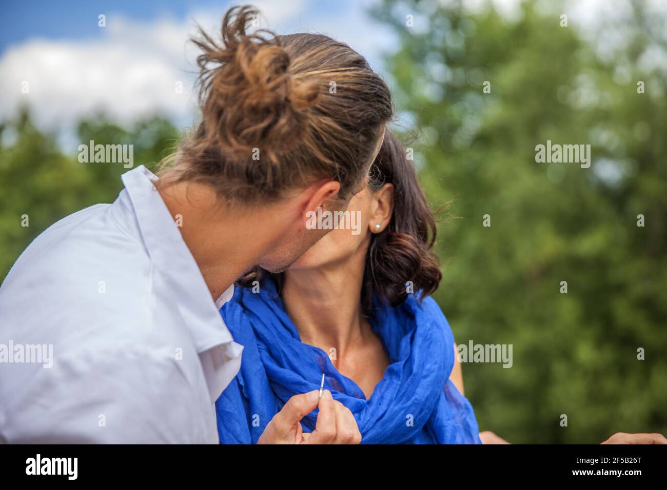 Cute Caucasian couple kissing and hanging a lock on the bridge as a ...