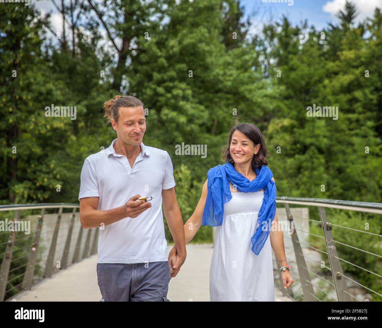 Cute Caucasian couple hanging a lock on the bridge as a sign of eternal ...