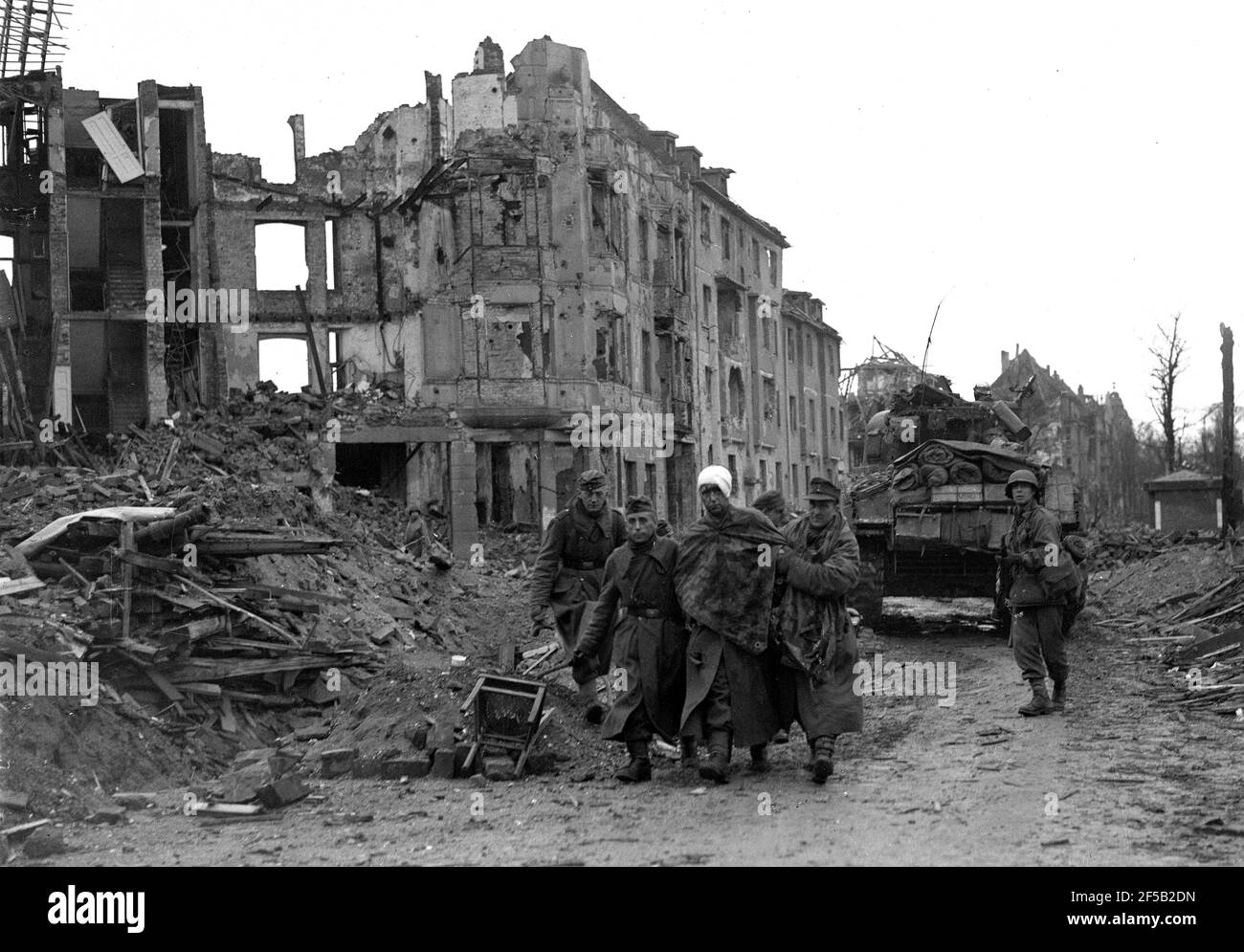 Cologne, Germany 1945 American troops escort injured captured German soldiers after they surrendered during World War Two following heavy bombing of the city. WW2 second world war. german defeat allied victory Deutschland 1940s surrender Europe European history destruction Stock Photo