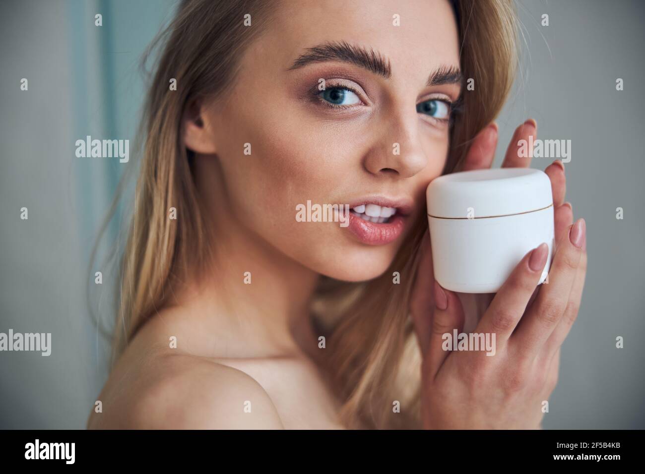 Tranquil woman with a cosmetic product posing for the camera Stock Photo