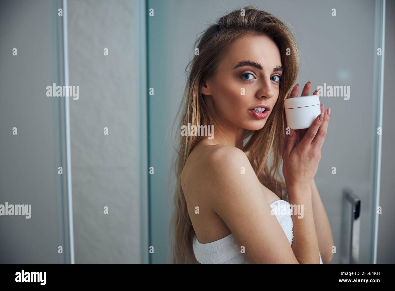 Attractive long-haired woman showing her beauty product Stock Photo