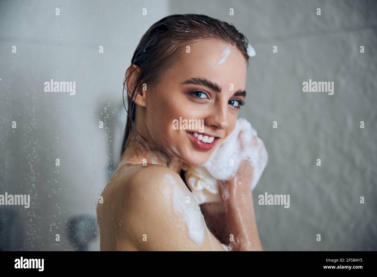rubbing herself with a washing cloth in the shower and lot of foam