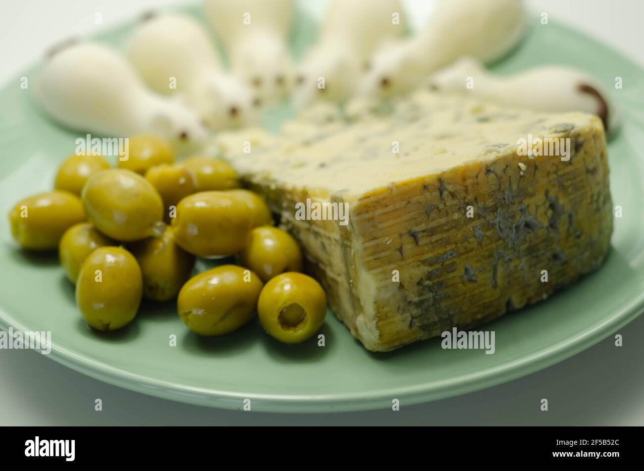 Full fat soft blue veined cheese with olives and snacks in the shape of