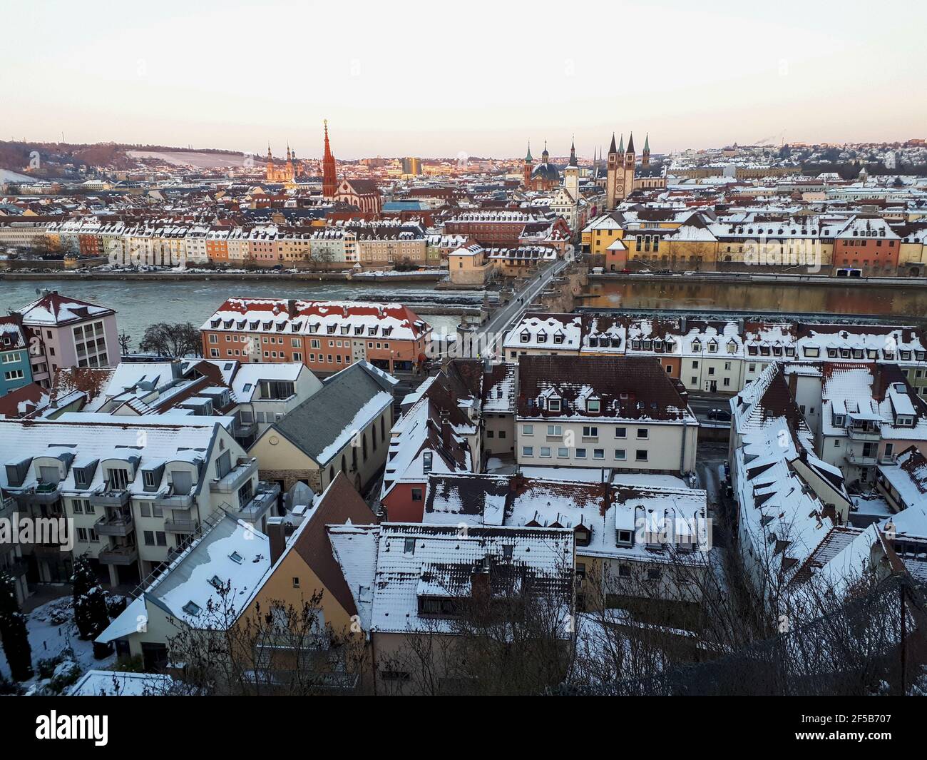 Cityscape of Wuerzburg with building roofs covered in the snow and Alte Mainbrücke in Würzburg, Germany Stock Photo