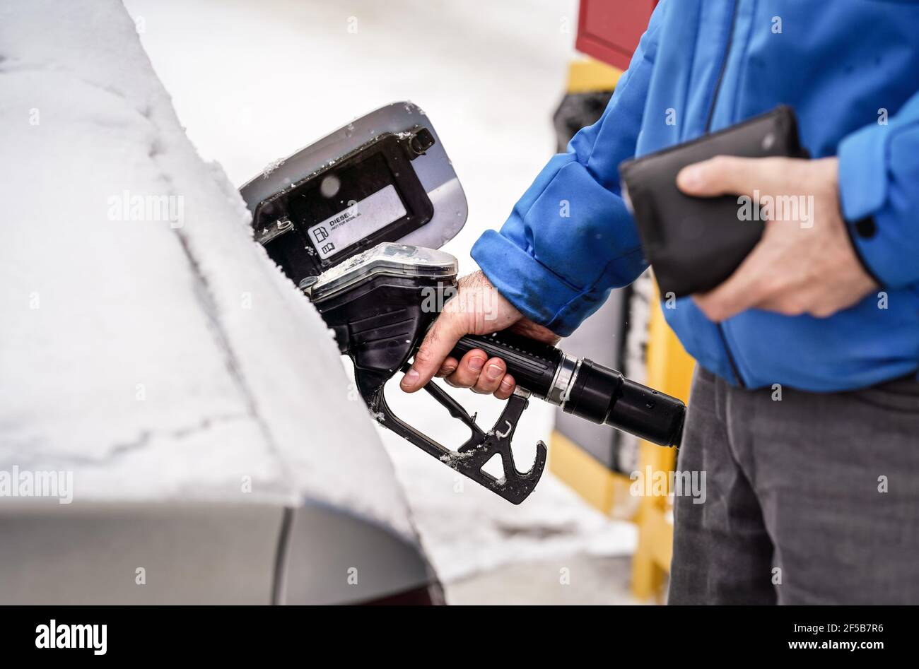 Man holding fuel nozzle, filling gas tank of diesel car covered with