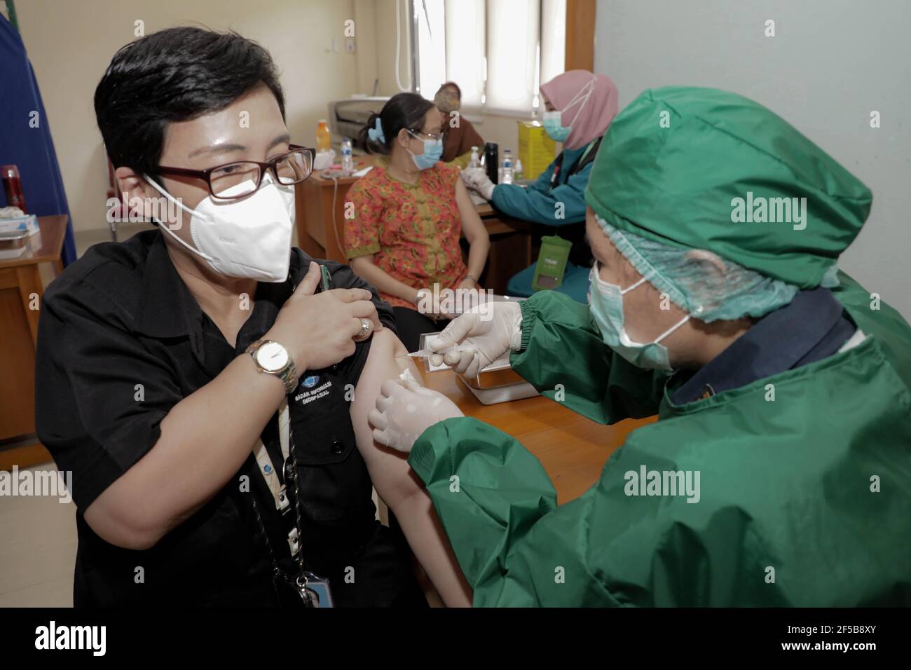A healthcare worker injects a dose of Sinovac COVID-19 vaccine to a worker during a mass vaccination drive for the public sector workers at Geospatial Information Agency Office in Bogor.Indonesia is currently in the second phase of mass covid-19 vaccination. In this second phase, the Indonesian government targets 38.5 million people, including 16.9 million workers in public sectors and 21.6 million elderly citizens, as well as workers in hospitality, transportation, tourism sectors and mass media workers. Stock Photo