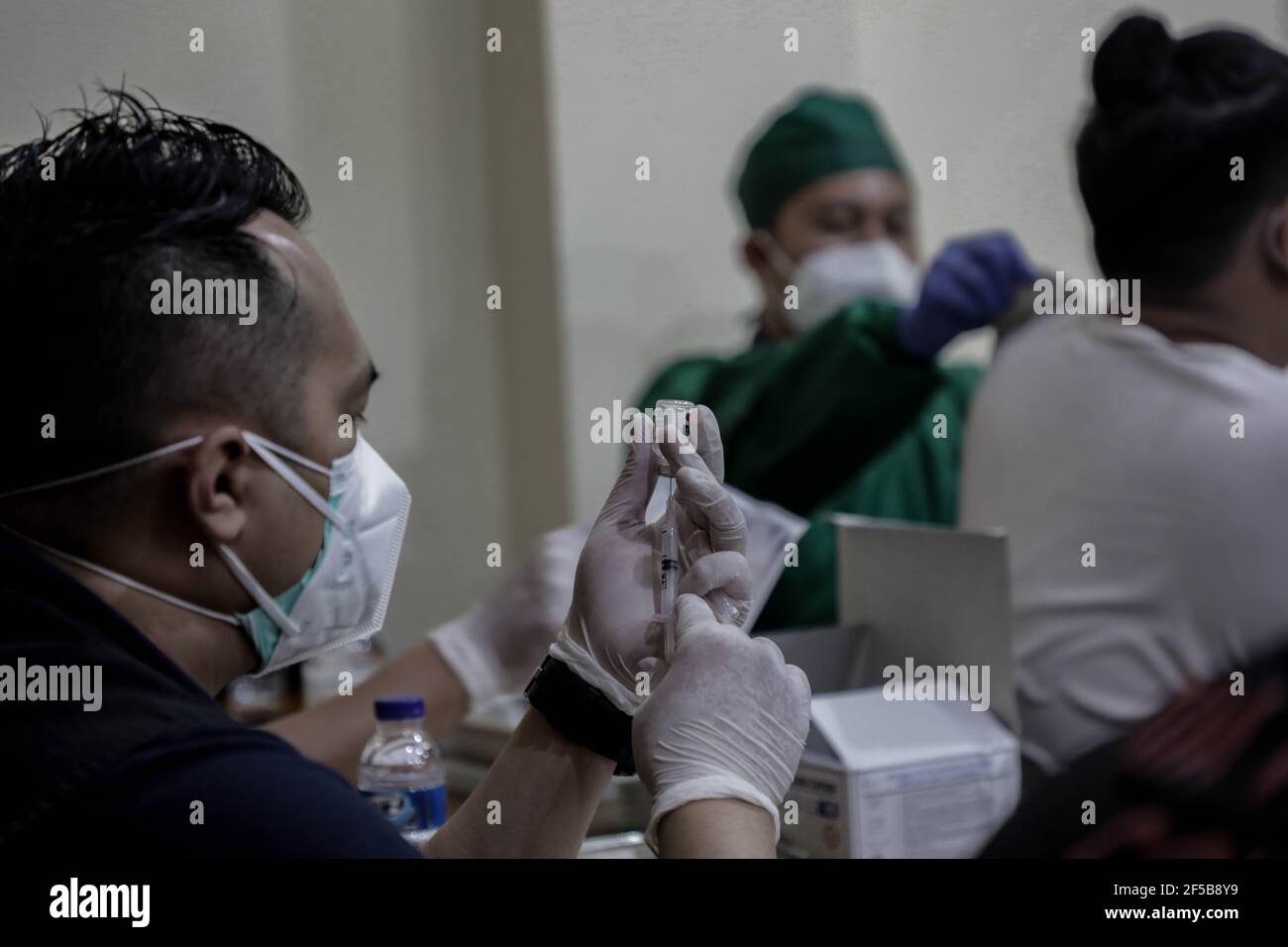 A healthcare worker preparing a dose of Sinovac COVID-19 vaccine during a mass vaccination drive for the public sector workers at Geospatial Information Agency Office in Bogor.Indonesia is currently in the second phase of mass covid-19 vaccination. In this second phase, the Indonesian government targets 38.5 million people, including 16.9 million workers in public sectors and 21.6 million elderly citizens, as well as workers in hospitality, transportation, tourism sectors and mass media workers. Stock Photo