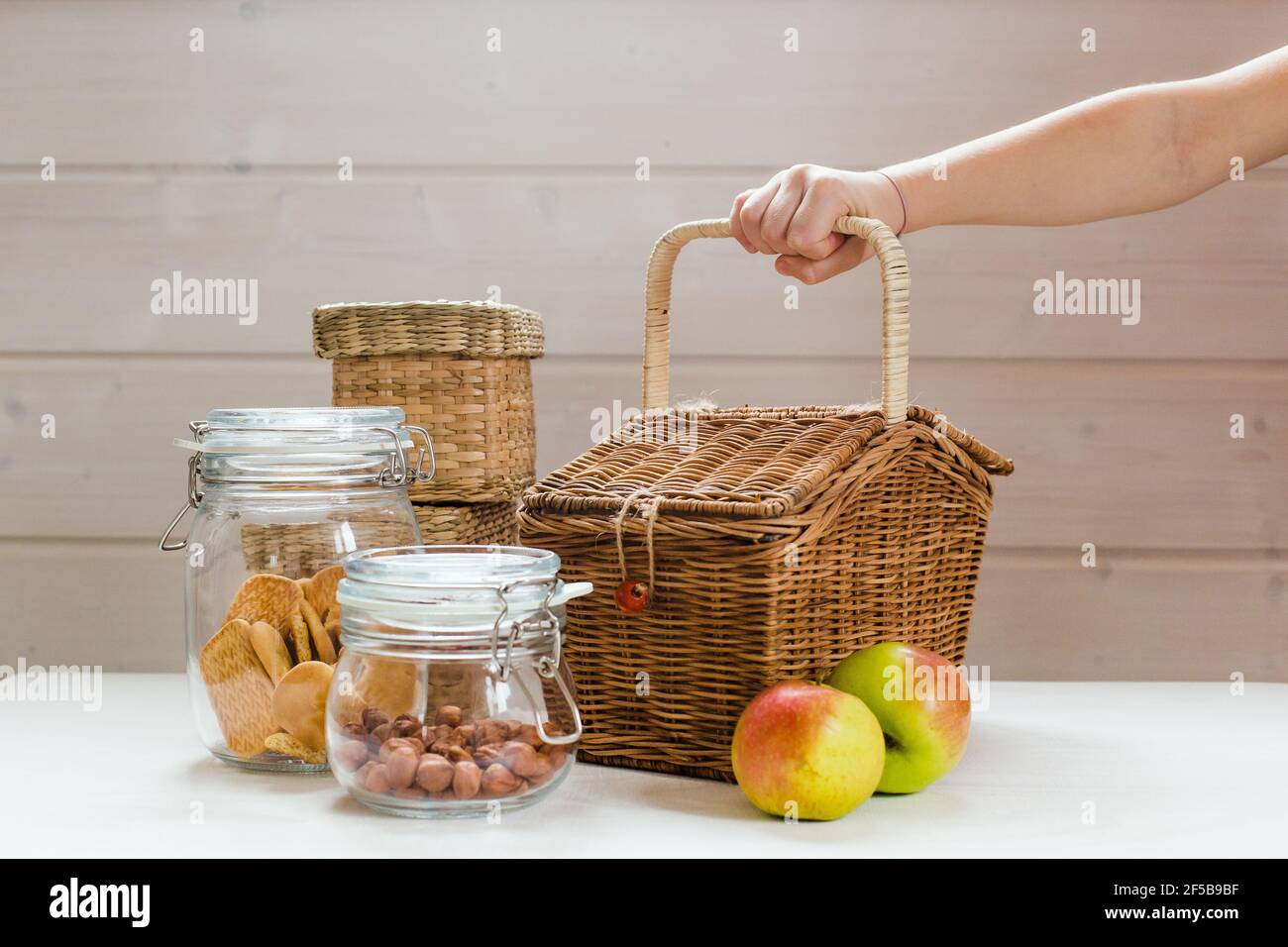 Glass cans with nuts and cookies and apples on wooden table, zero waste picnic concept child hand Stock Photo
