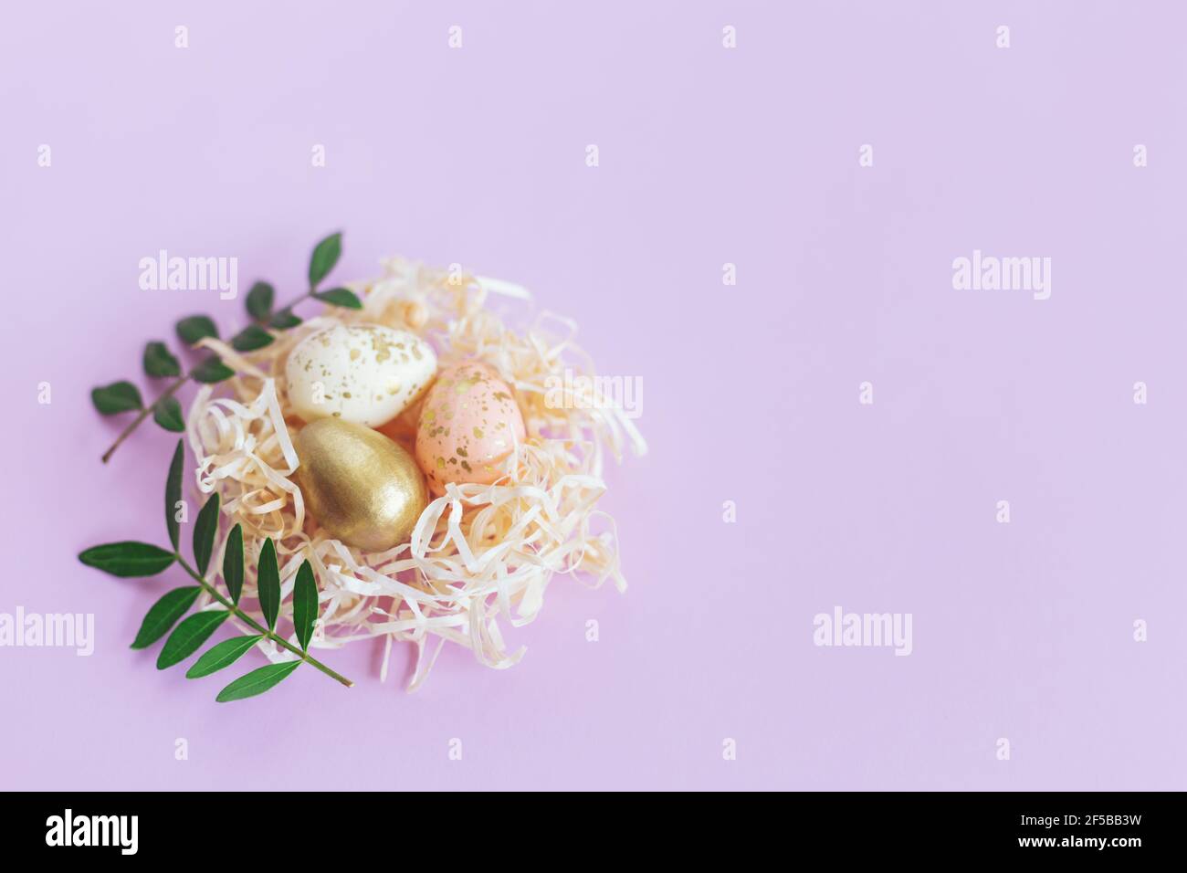 Easter background with eggs in a nest and green leaves. Pastel colors ...