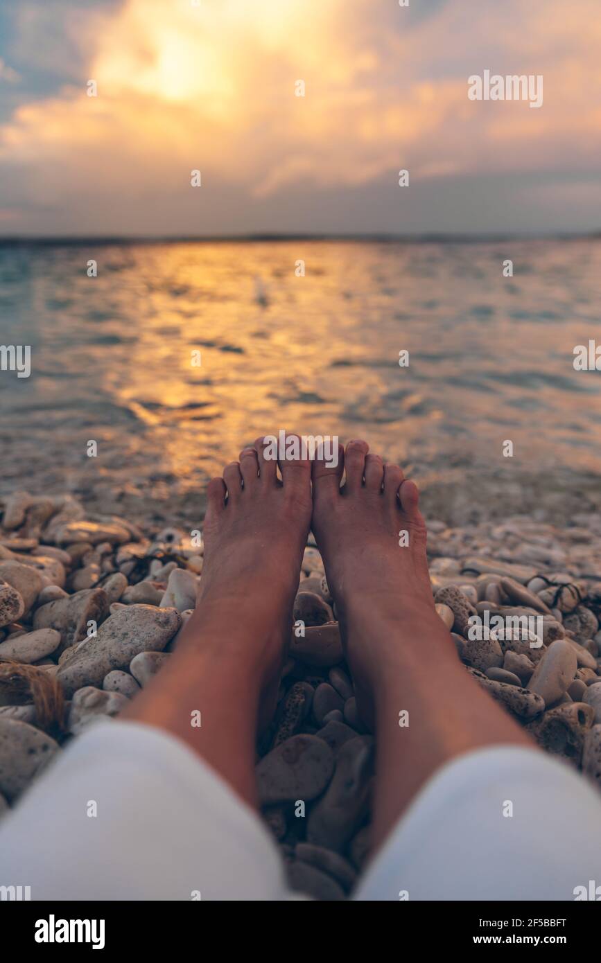 woman laying at the beach looking on sunset above sea. body parts legs ...