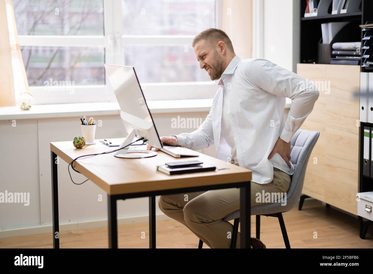 Bad Posture Sitting At Office Desk Using Computer Stock Photo