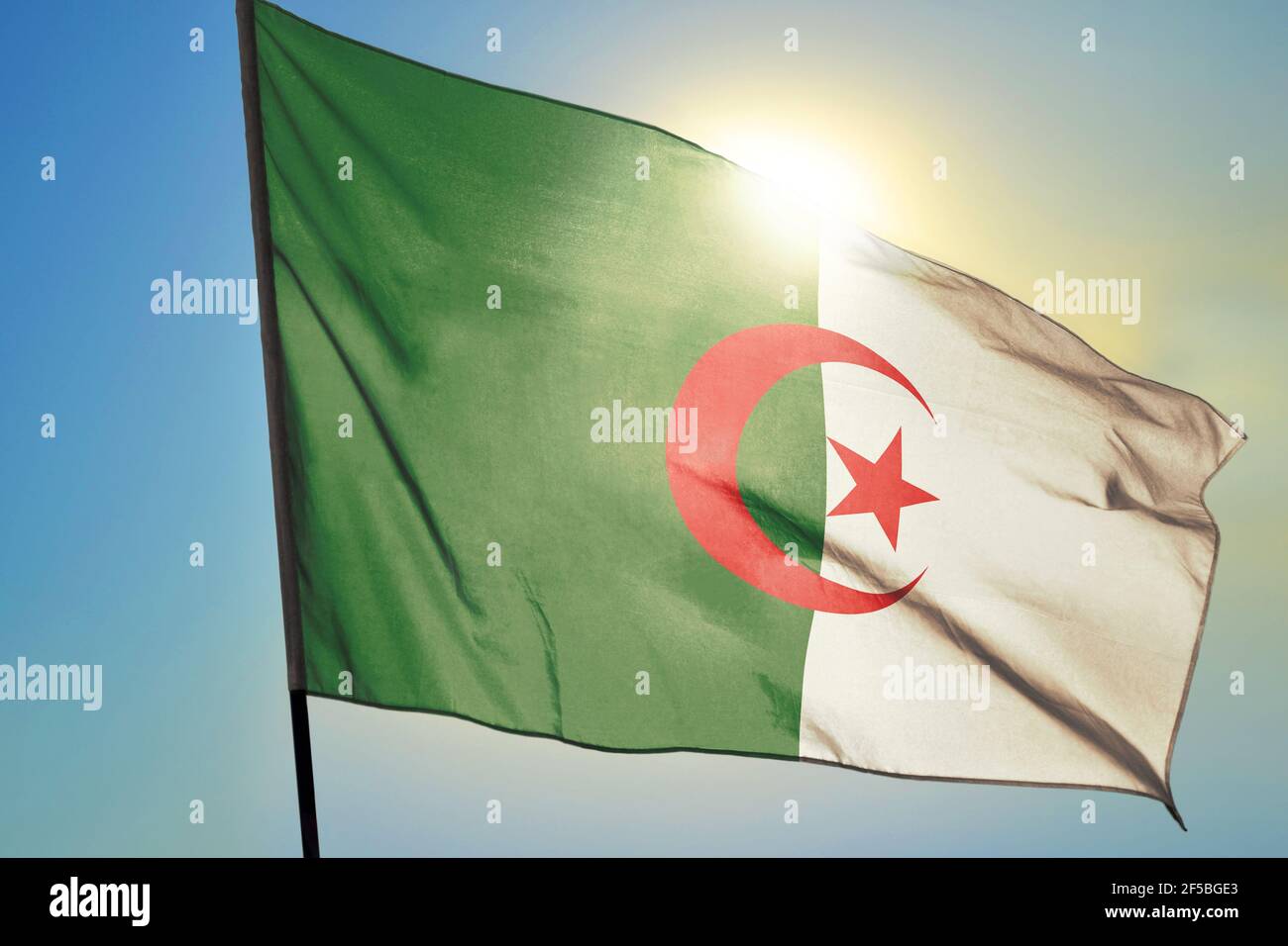 Algeria flag waving on the wind in front of sun Stock Photo