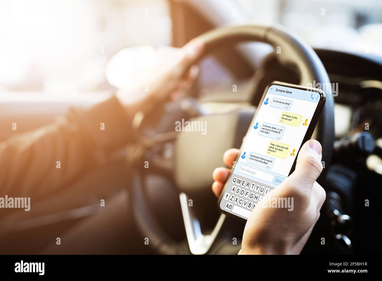 Man Typing Text Message On Mobile Phone While Driving Car Stock Photo