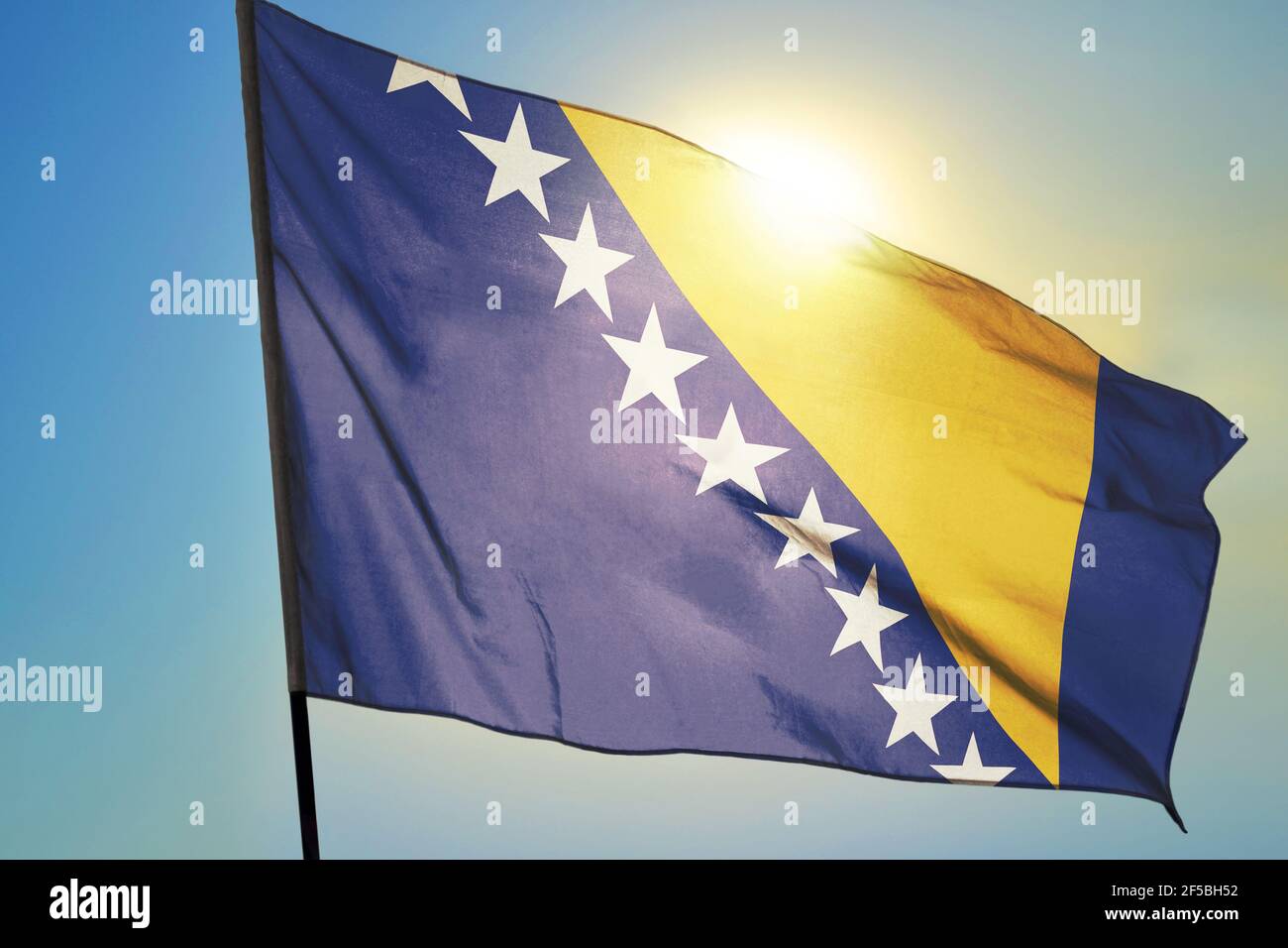 Bosnia and Herzegovina flag waving on the wind in front of sun Stock Photo