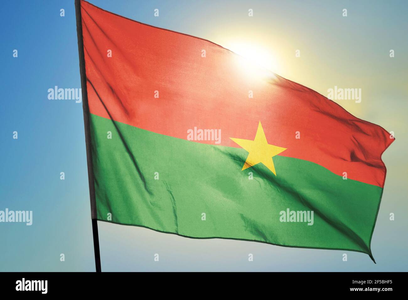 Burkina Faso flag waving on the wind in front of sun Stock Photo