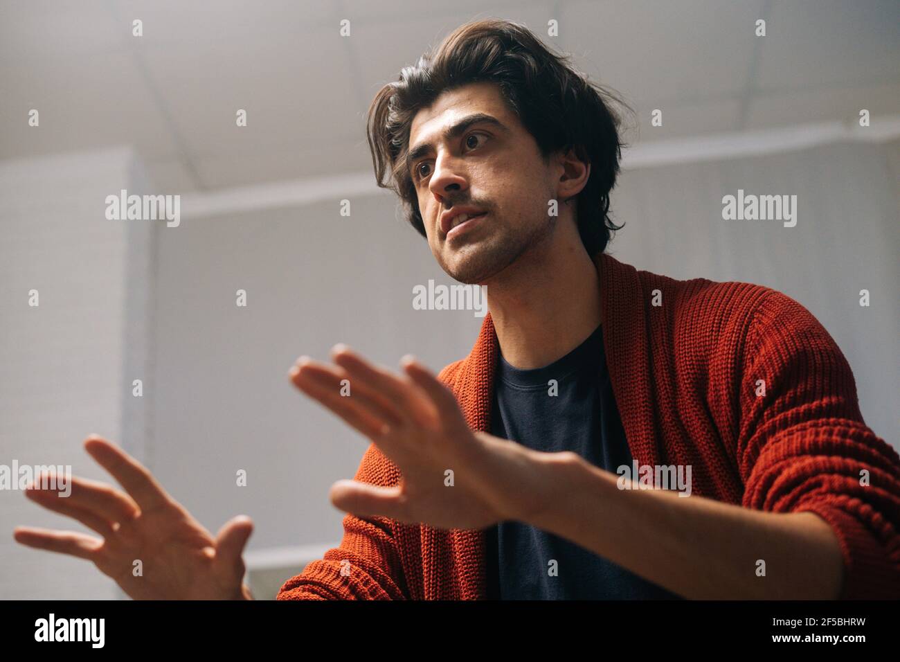 ow-angle view of professional music teacher explaining gesturing to student how to play on musical instrument during lesson. Stock Photo