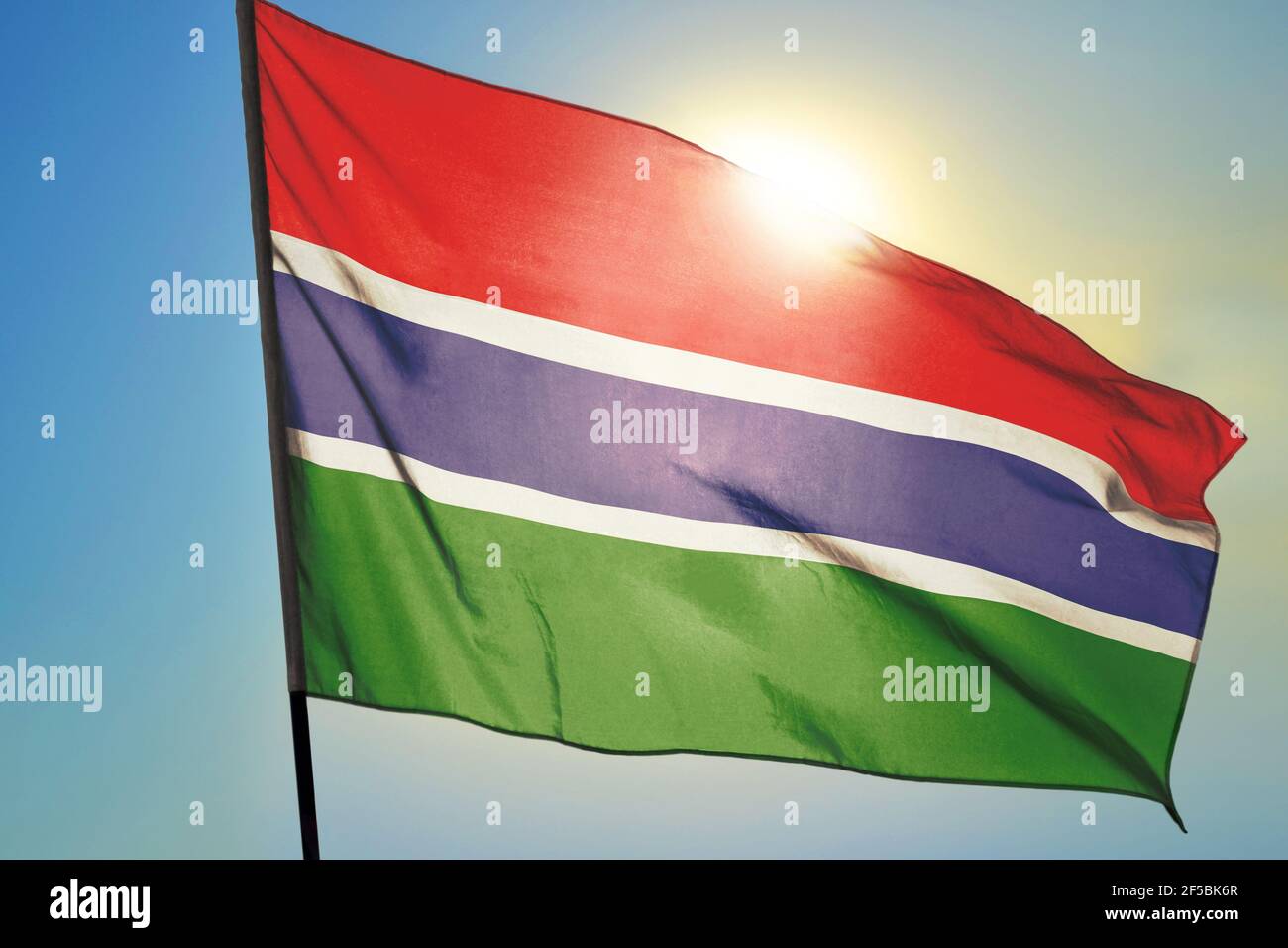 Gambia flag waving on the wind in front of sun Stock Photo