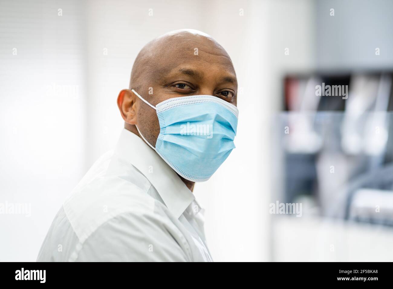Receptionist Man Wearing Medical Mask At Office Reception Stock Photo