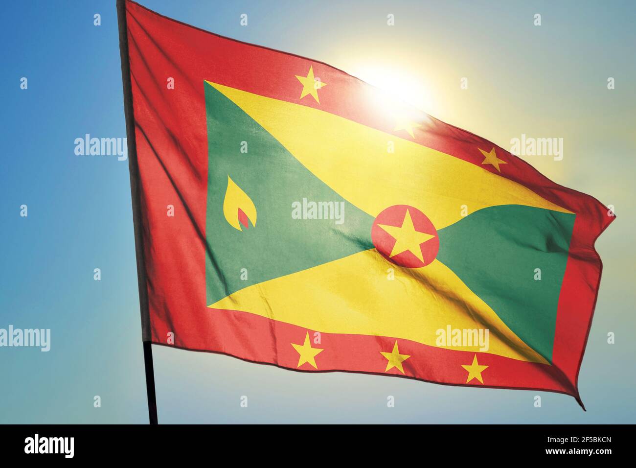 Grenada flag waving on the wind in front of sun Stock Photo