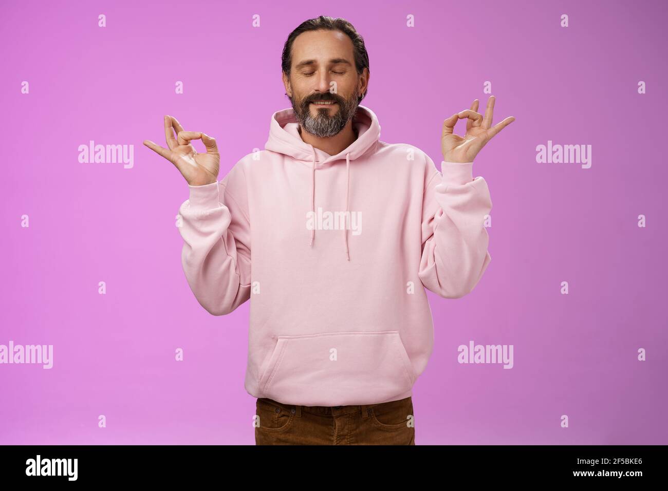 Peaceful charming hipster old man wearing cool pink hoodie close eyes  breathing practice release stress meditating standing relaxed happy yoga  Stock Photo - Alamy