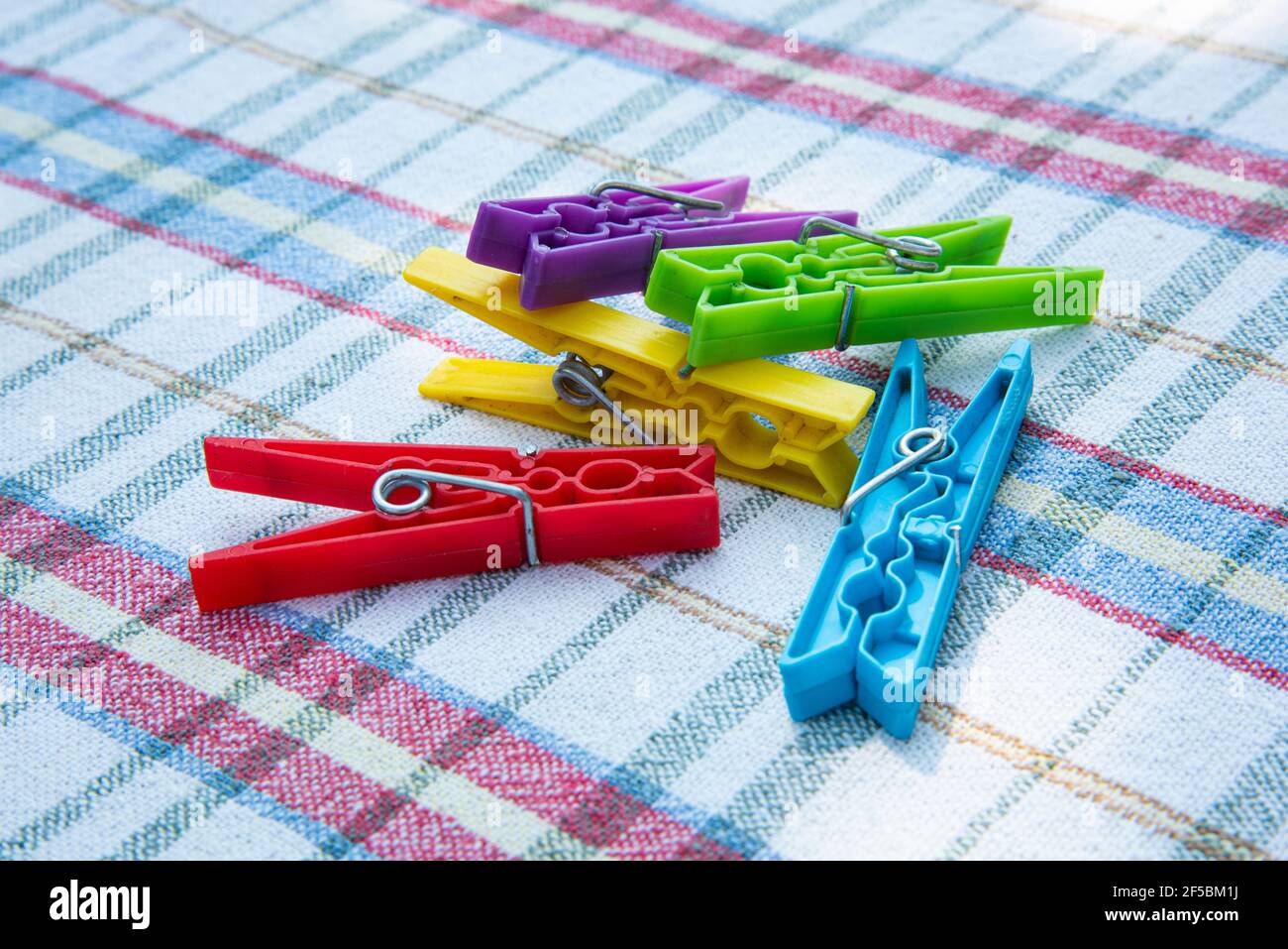 purple, green, yellow, red and blue pegs. colorful clothes pegs on cloth. plastic latches Stock Photo