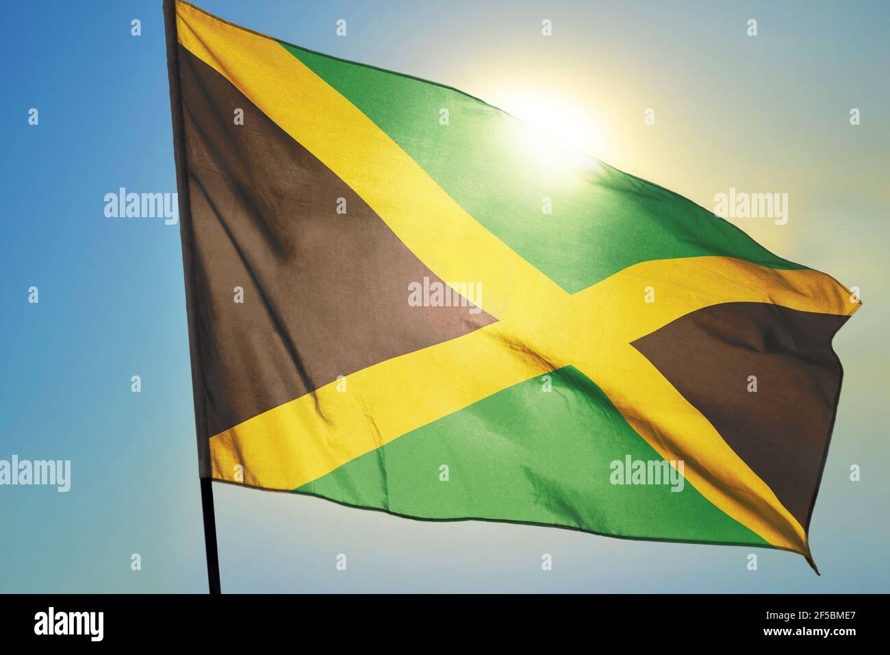 Jamaica flag waving on the wind in front of sun Stock Photo