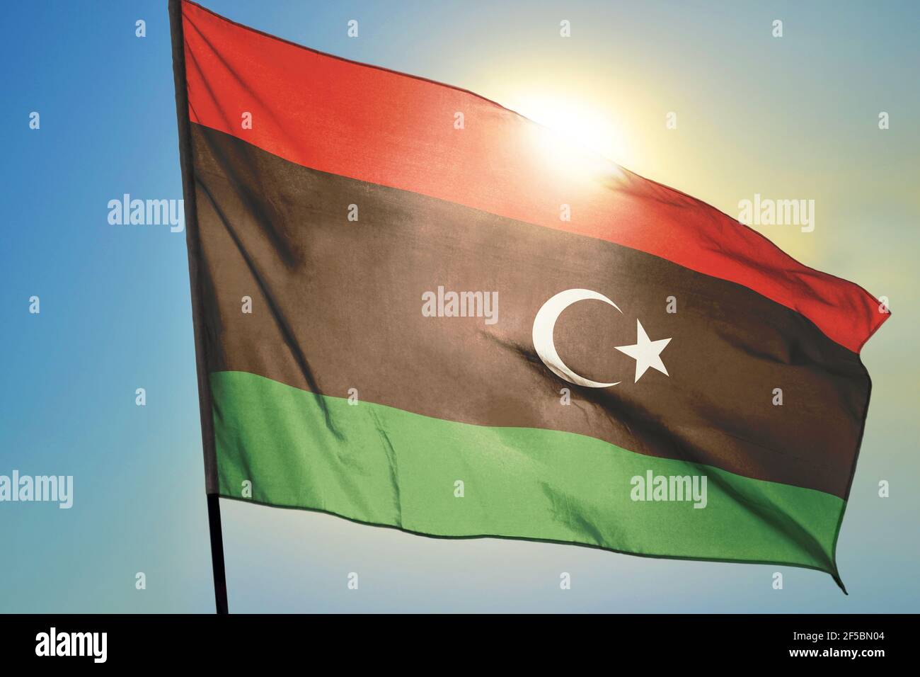 Libya flag waving on the wind in front of sun Stock Photo - Alamy
