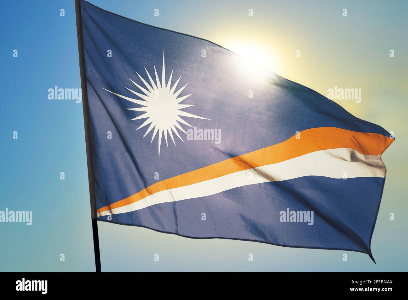 Marshall Islands flag waving on the wind in front of sun Stock Photo