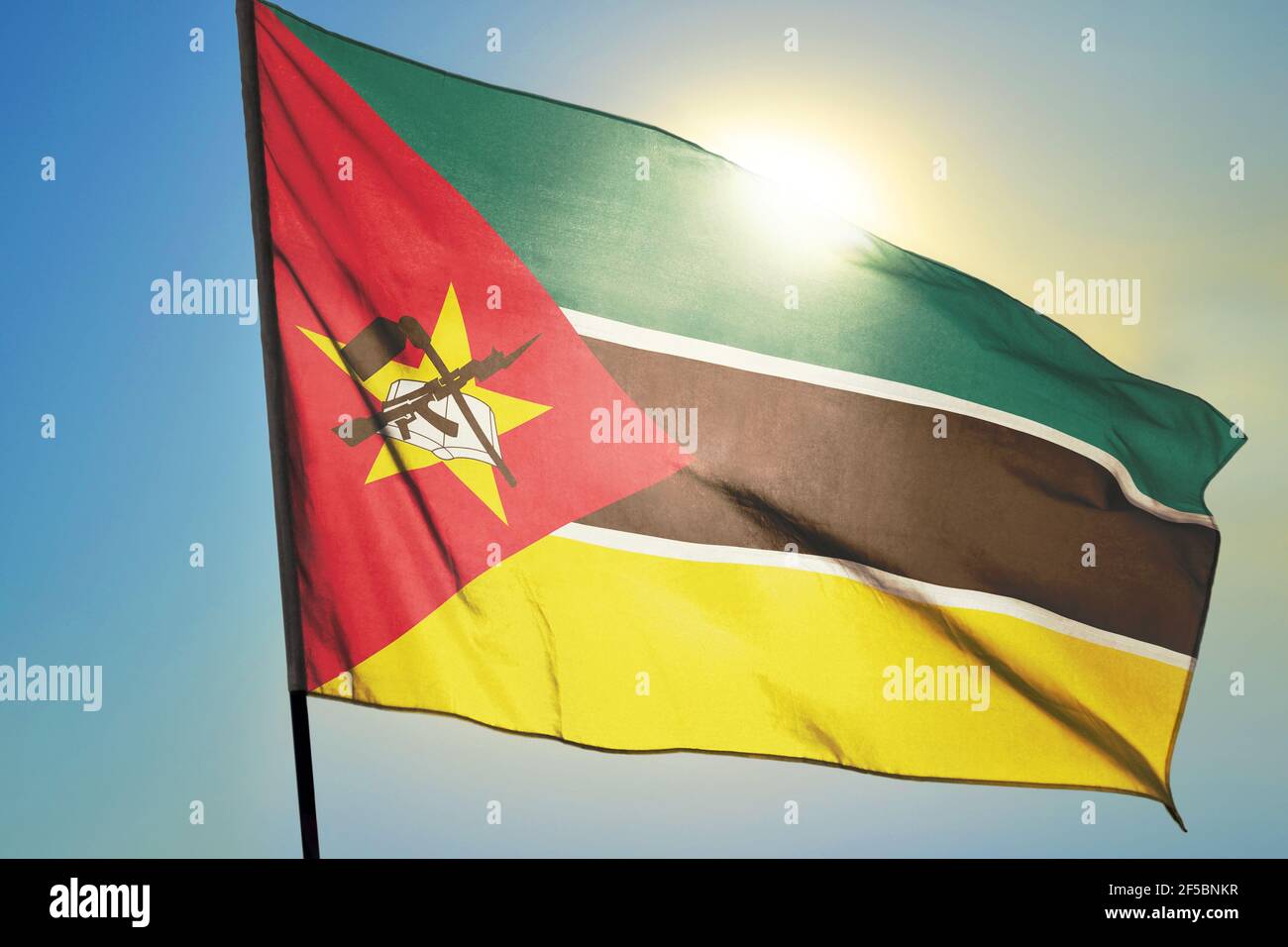 Mozambique flag waving on the wind in front of sun Stock Photo