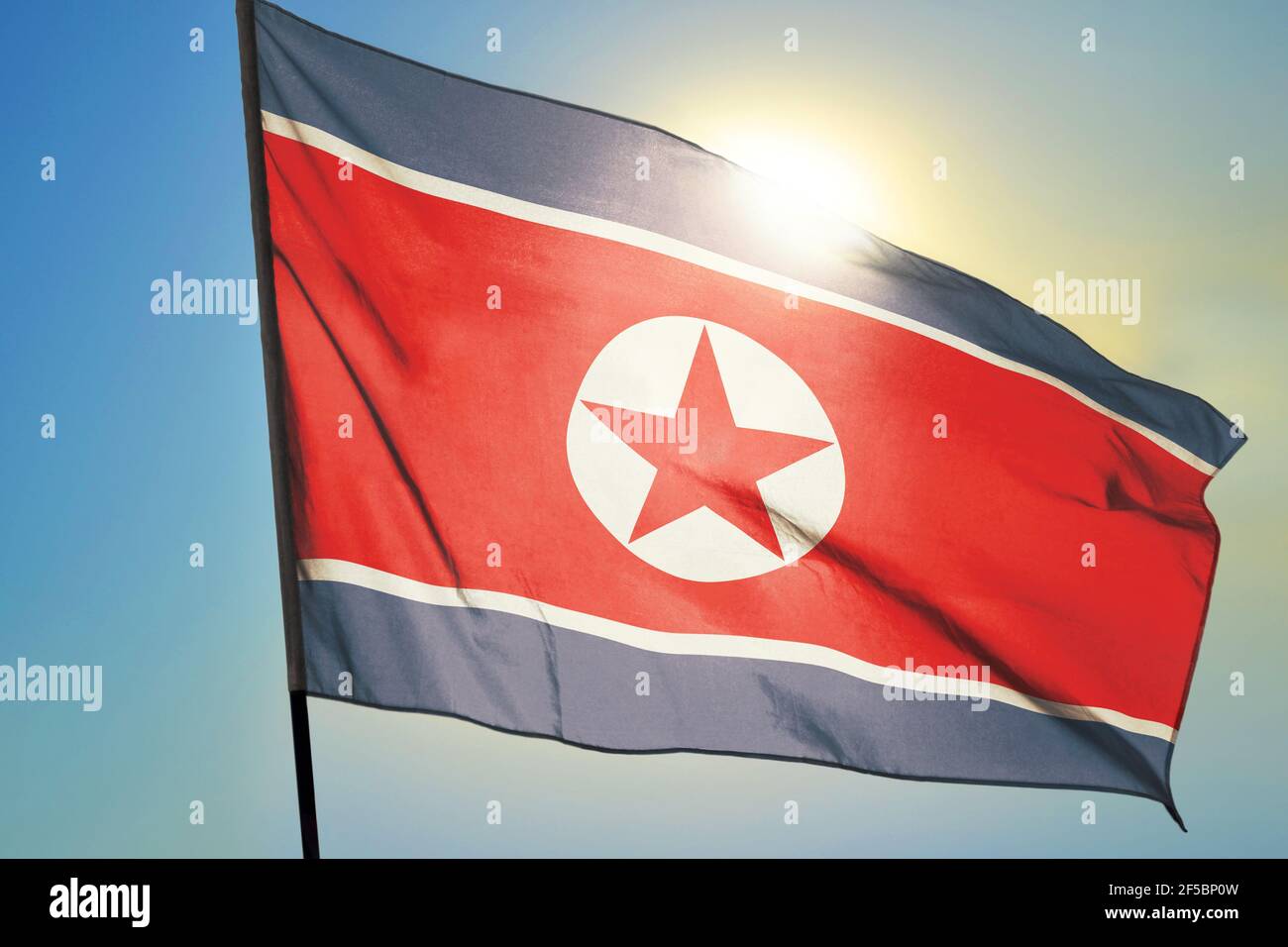 North Korea flag waving on the wind in front of sun Stock Photo