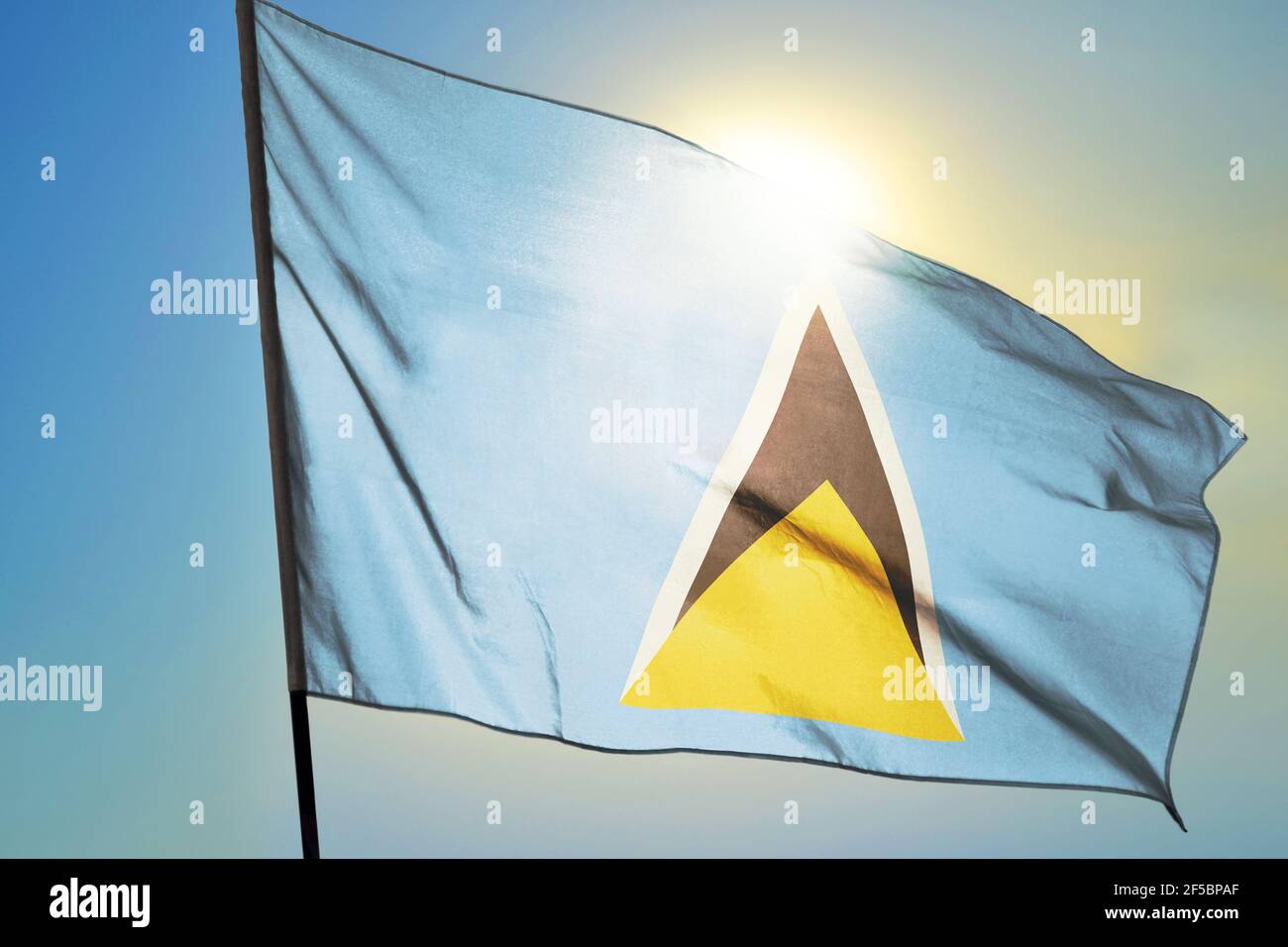 Saint Lucia flag waving on the wind in front of sun Stock Photo