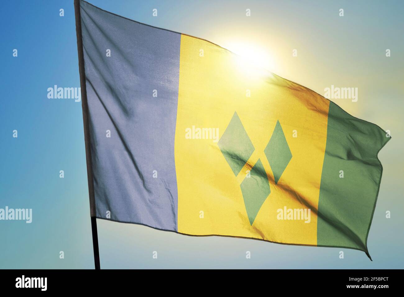 Saint Vincent and the Grenadines flag waving on the wind in front of sun Stock Photo