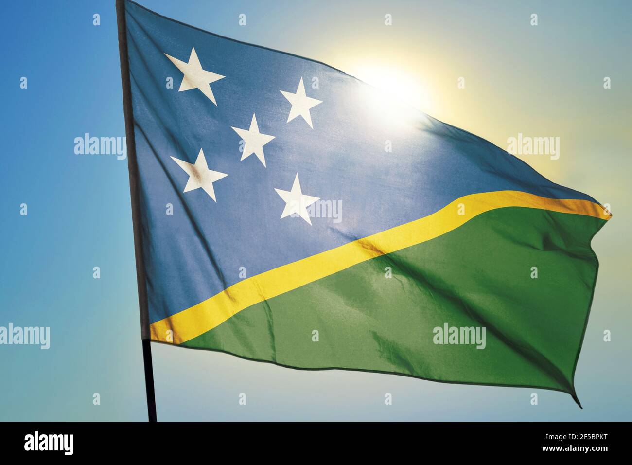 Solomon Islands flag waving on the wind in front of sun Stock Photo