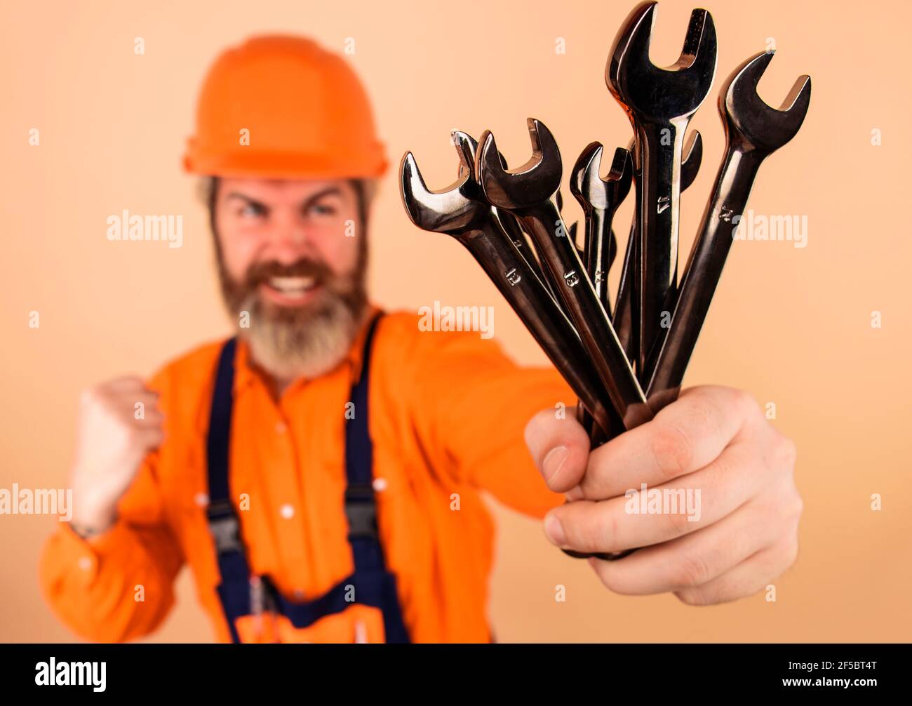Repairment tools. Smiling worker with wrenches. Builder in construction helmet with Spanners