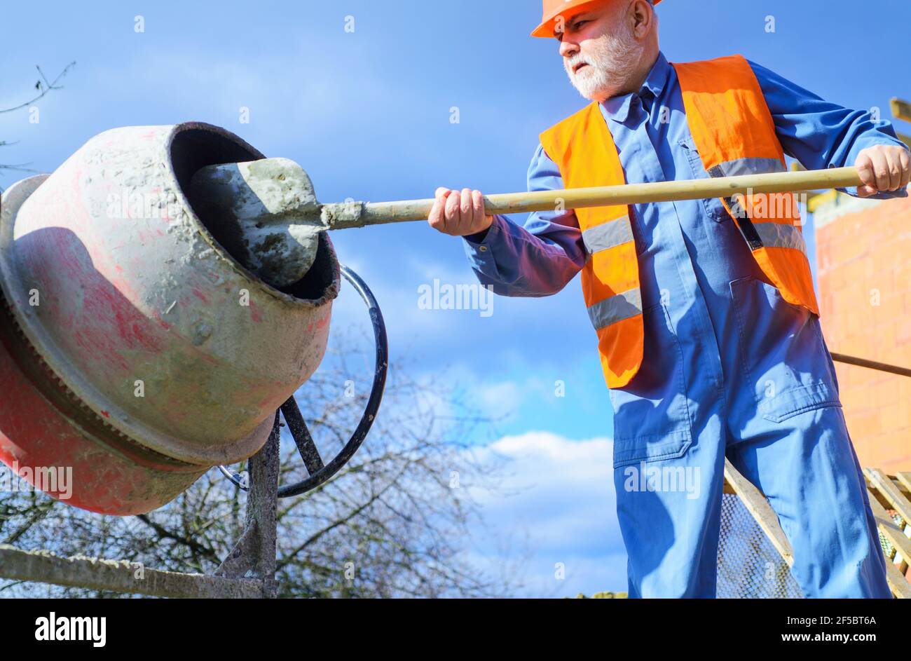 Builder with concrete mixer prepares cement mortar. Construction worker