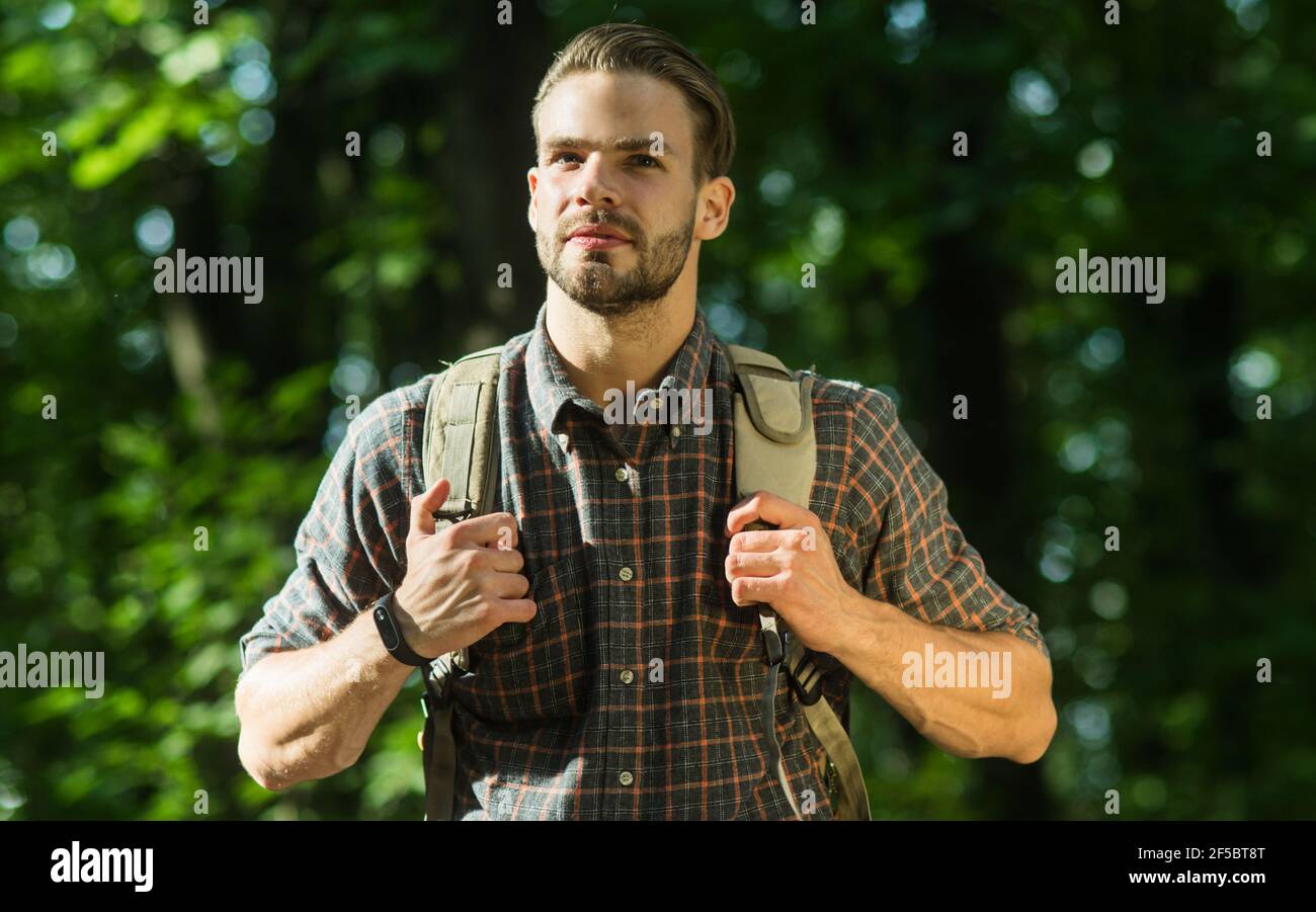 Man traveler with backpack. Happy hiker in forest. Attractive man with traveling rucksack. Stock Photo