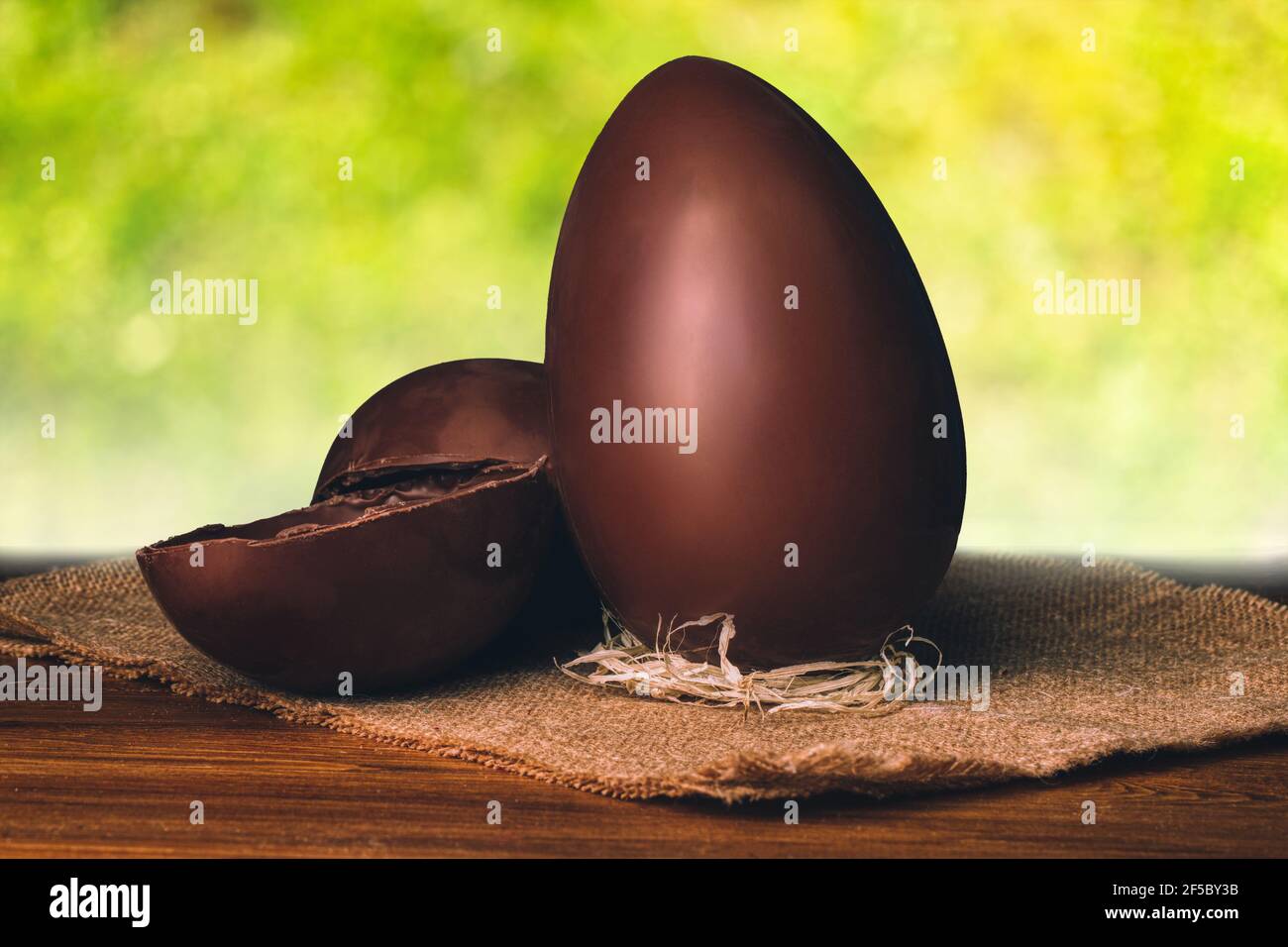 Chocolate Easter eggs and blurred green nature background. Natural template with beauty bokeh and warm sunlight. Concept banner for products display Stock Photo