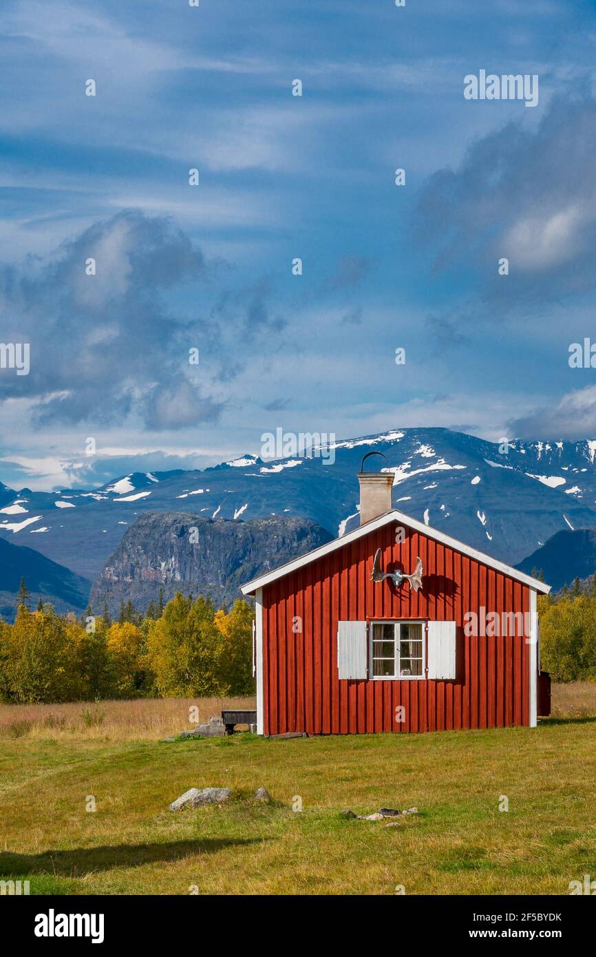 Red wooden house in arctic wilderness. Aktse mountain cabin deep in Sarek National Park, Sweden. Antlers on the wall. Sunny day of autumn in the Stock Photo