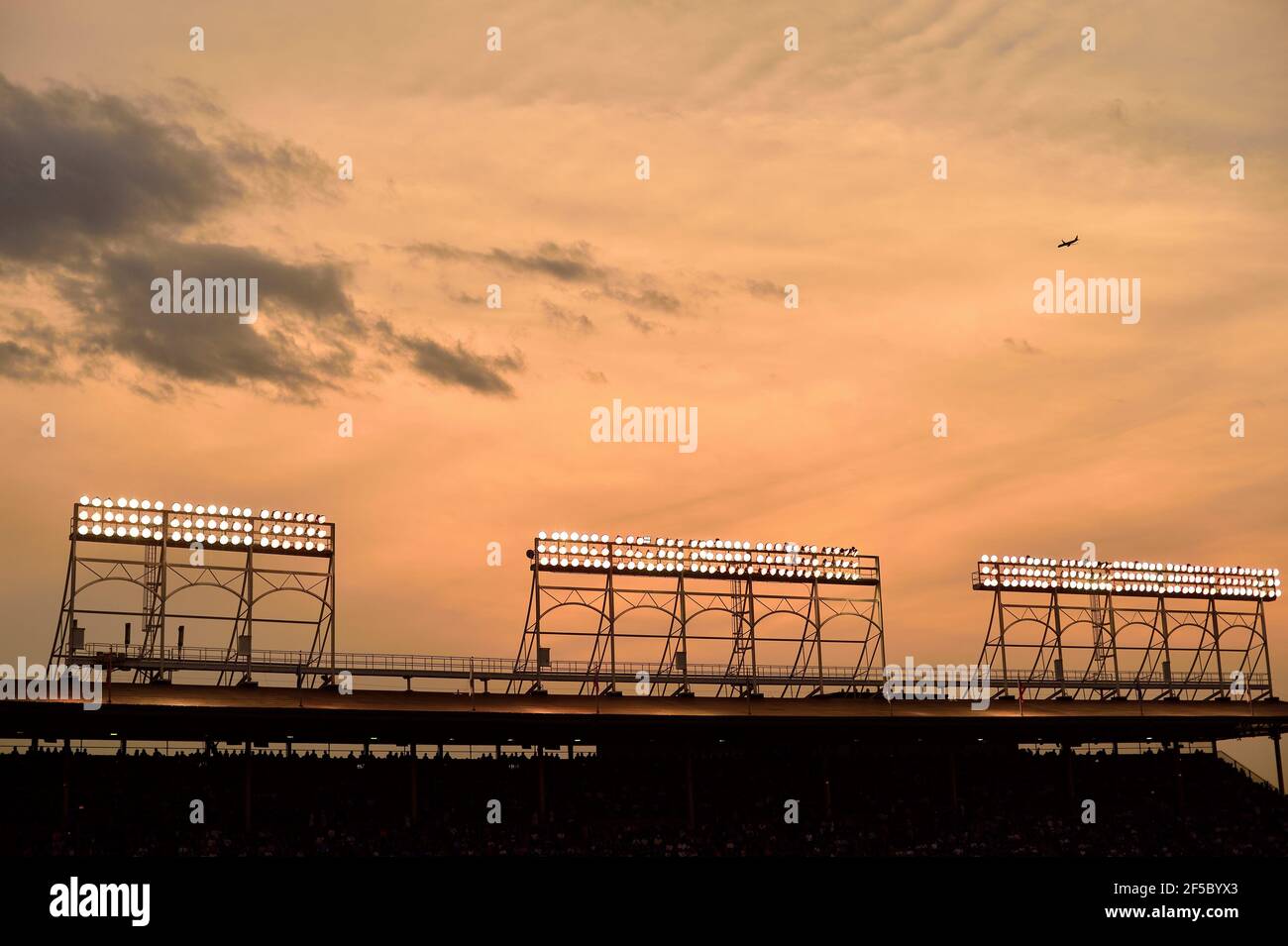 Chicago, Illinois, USA. The sun setting beyond the light towers on the grandstand of Wrigley Field during a night game. Stock Photo