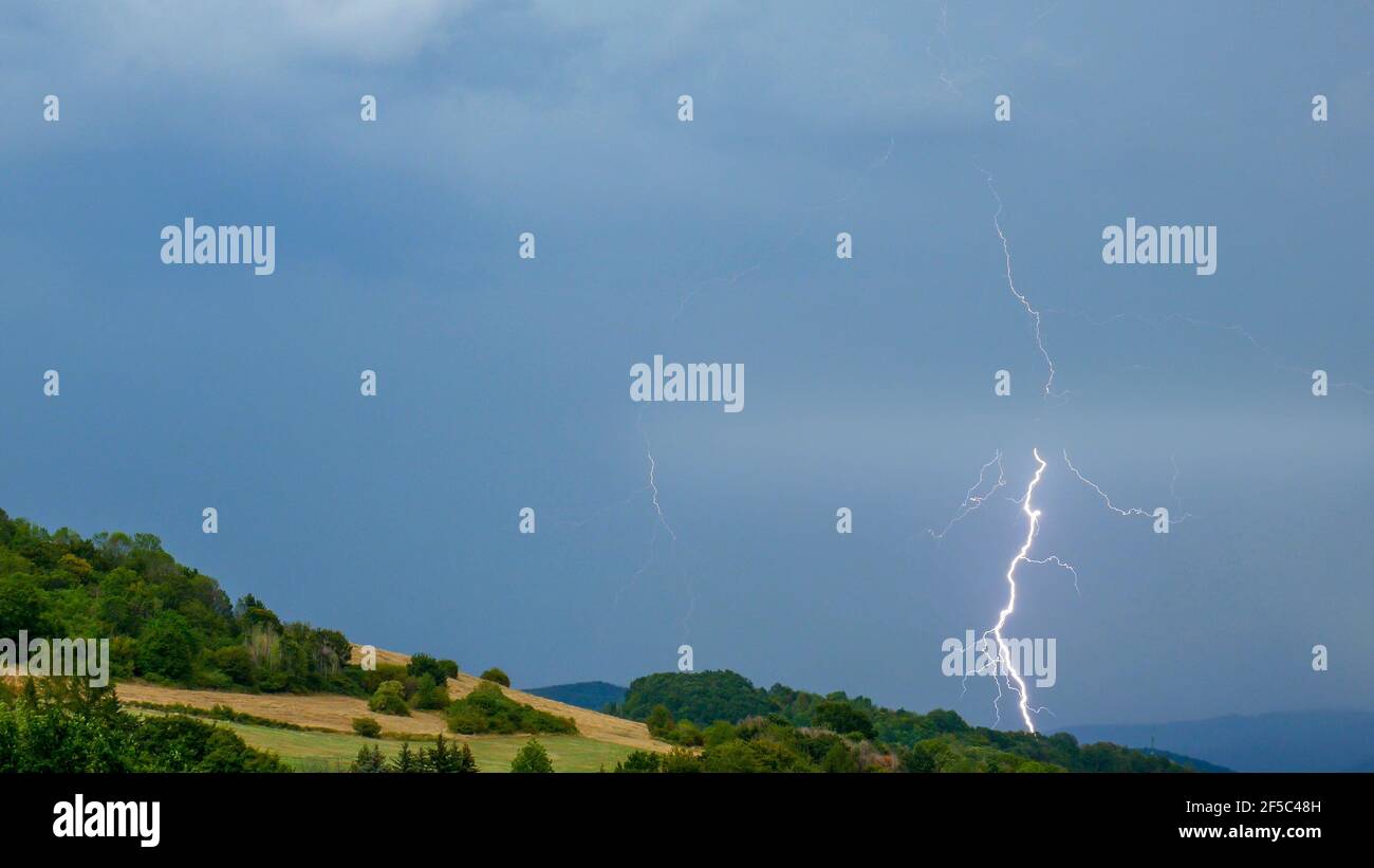 Storm with lightning over the hilly landscape Stock Photo